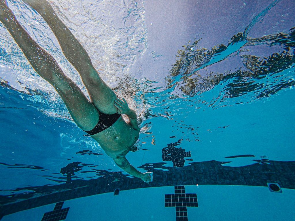 Underwater view of a male swimmer training in a pool, showcasing athleticism.